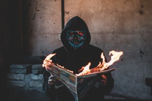 person holding a burning newspaper