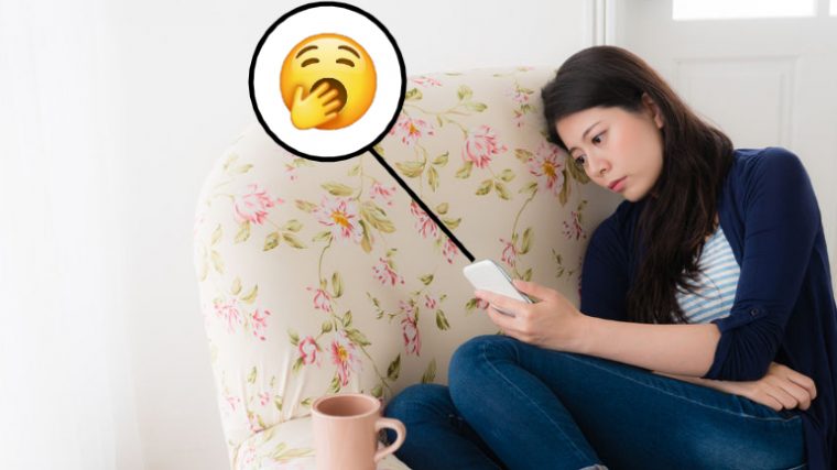 A girl sitting on the couch on her phone looking sad and bored