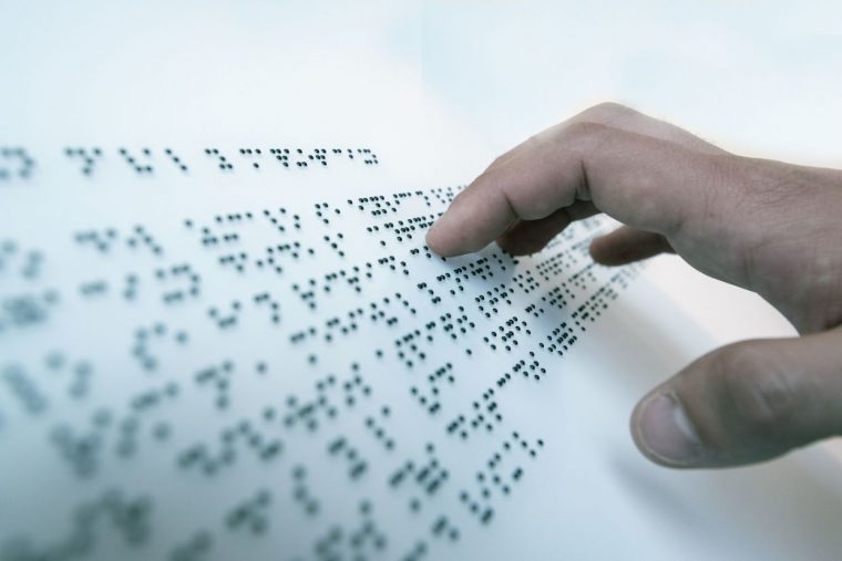 Hand of a blind person reading a text in the language of the blind, Braille.