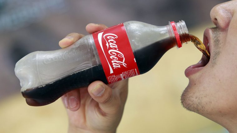 man chugging down a bottle of coca cola