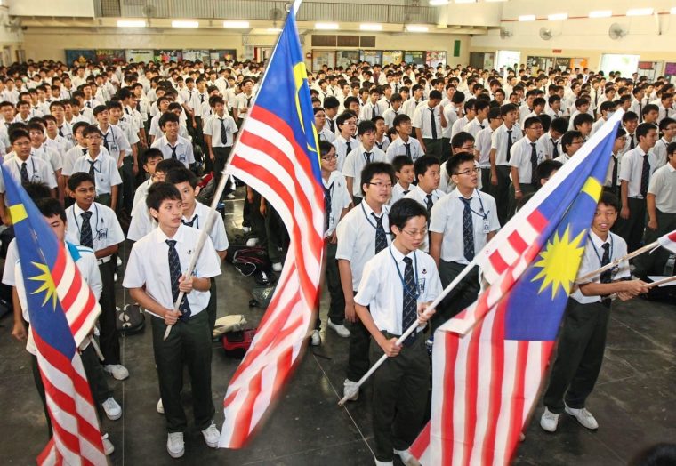 Students of a school waving Malaysian flag and singing Merdeka songs