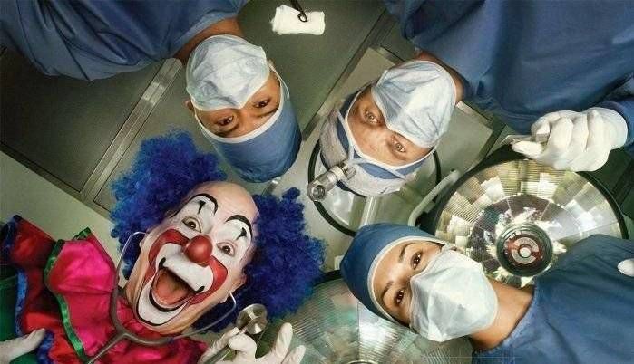group of doctors and one clown looking down at a patient