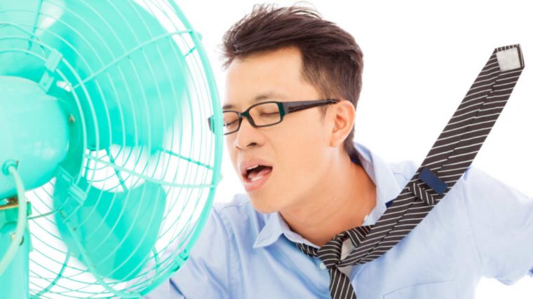 man staying cool by standing in front of a fan