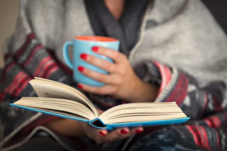 Woman reading a book while drinking tea