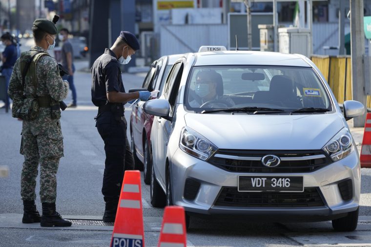 policeman at road block checking a driver's temperature