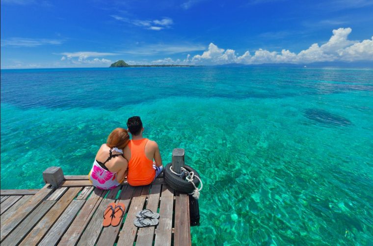 Malaysian couple relaxing on a jetty by the seashore