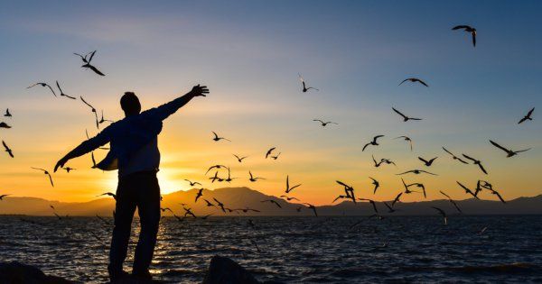 man standing on the beach dramatically facing the sunset