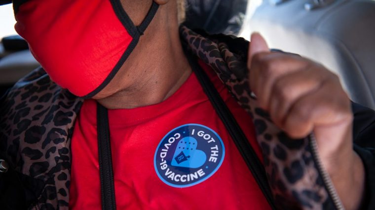 recently vaccinated woman showing her badge as proof