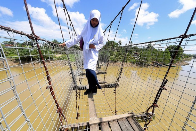 SANDAKAN, 10 Jan — Seorang pelajar Sekolah Kebangsaan Sibuga Besar meniti pada sekeping papan yang dijadikan lantai jambatan gantung yang sudah usang pada hari pertama sesi persekolahan ketika tinjauan di Kampung Nelayan Tengah hari ini. --fotoBERNAMA (2022) HAK CIPTA TERPELIHARA